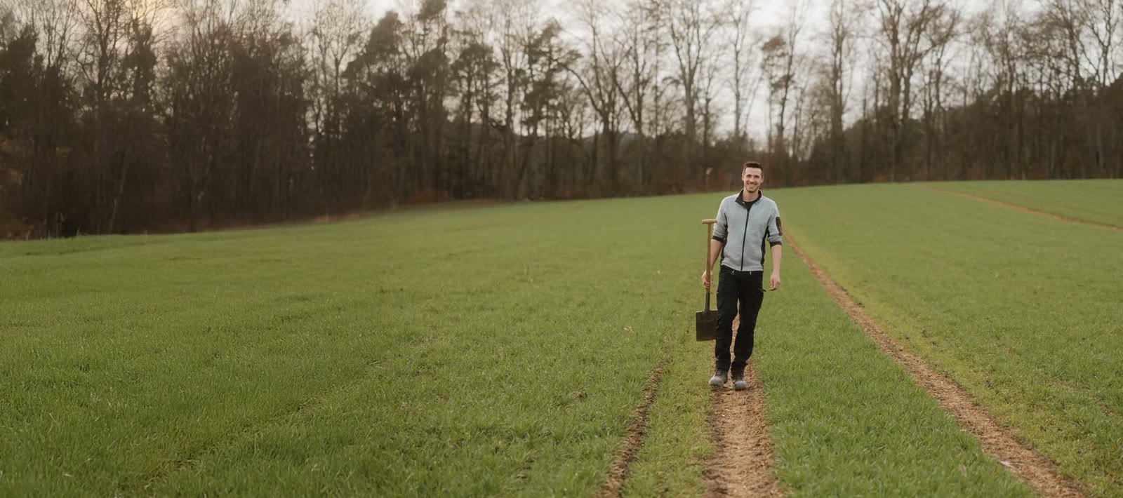 Simon Martin läuft mit einem Eimer über ein grünes Feld