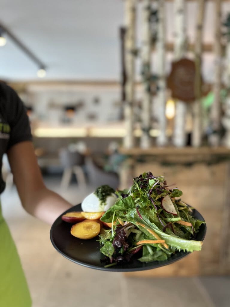 Mitarbeiterin serviert einen Salatteller im Hofcafé